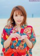 A woman in a colorful kimono standing on a beach.