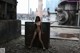 A naked woman standing in front of an industrial building.