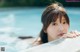 A young woman leaning on the edge of a swimming pool.