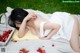 A woman laying on a blanket next to a basket of cherries.