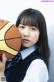 A young woman holding a basketball in her hand.