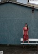 A woman in a red dress sitting on a white bench.