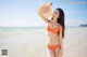 A woman in an orange bikini standing on a beach.