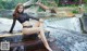 A woman sitting on a wooden dock next to a waterfall.