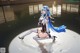 A woman with long blue hair is sitting in the water.