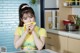 A woman in a kitchen wiping her face with a yellow towel.