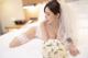 A woman laying on a bed holding a bouquet of flowers.