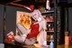 A woman in a red dress sitting on a bar.