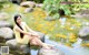 A woman sitting on a rock in a pond.