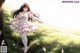 A girl in a pink dress is walking through a grassy field.