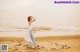 A woman standing on a beach next to the ocean.