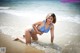 A woman in a blue bikini sitting in the water.