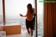A woman standing in front of a window with a view of the city.