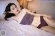 A woman laying on a bed in a purple lingerie.