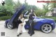 A couple of women standing next to a blue sports car.