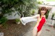 A woman in a red and yellow bathing suit holding a white scarf.