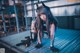 A woman in a black outfit crouching down on a metal platform.